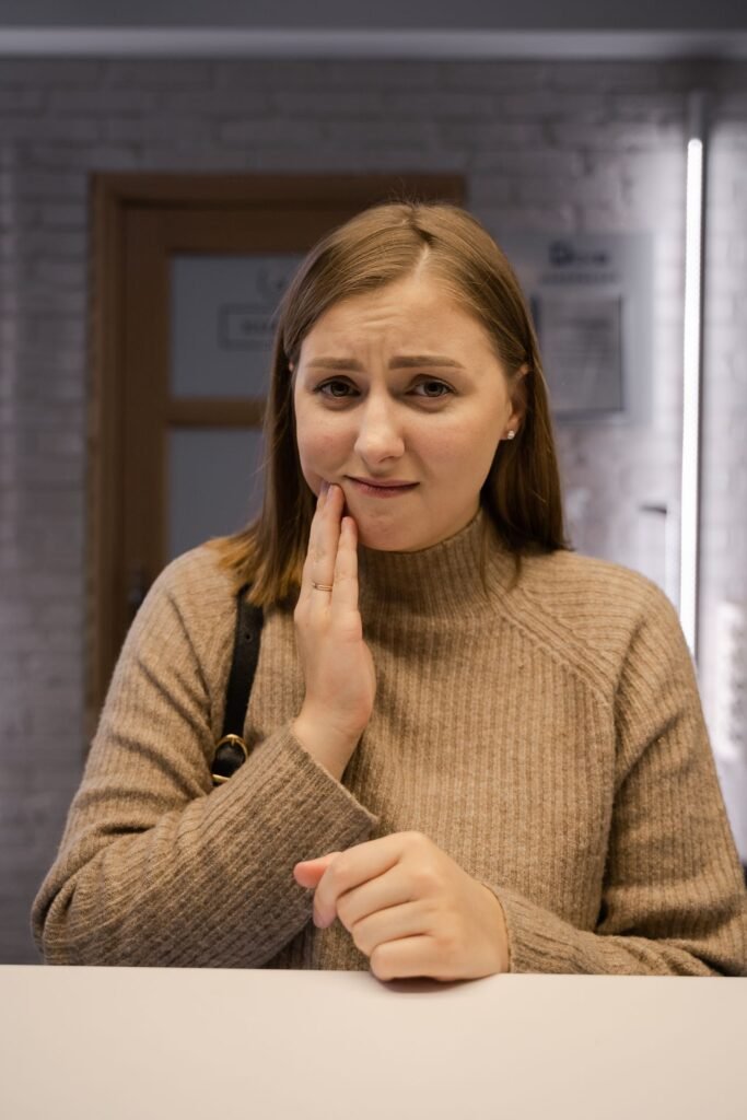 Woman holding her cheek because of throbbing pain from a possible tooth abscess