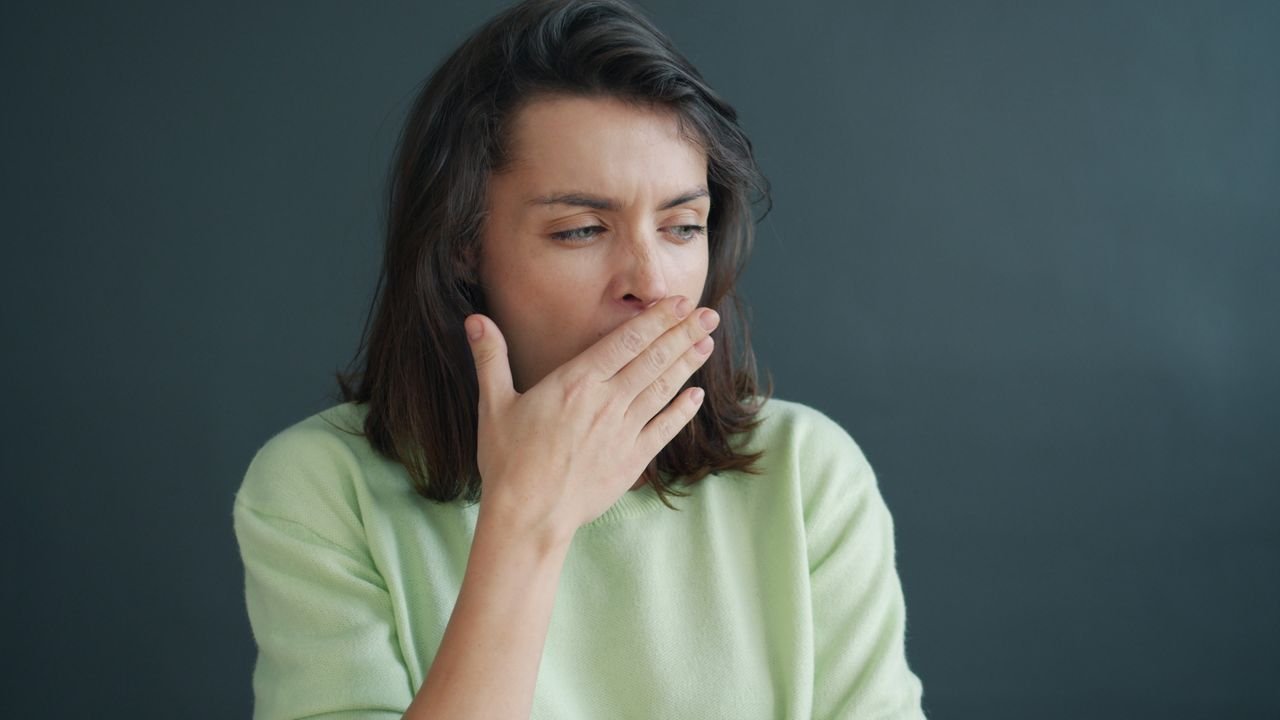 Person covering their mouth, worried about bad breath that won't go away